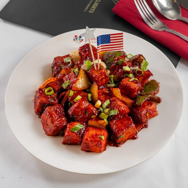 Pariwaar Delights' chili paneer, garnished with green onions and an American flag pick.