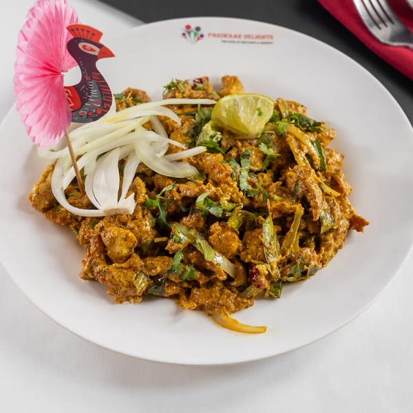 Pariwaar Delights' Indian chicken dish, garnished with onions, cilantro, lime, and a peacock decoration.
