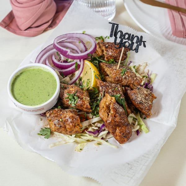 Pariwaar Delights' Indian seekh kebabs with green chutney, red onion, lemon, and a "Thank You" pick.