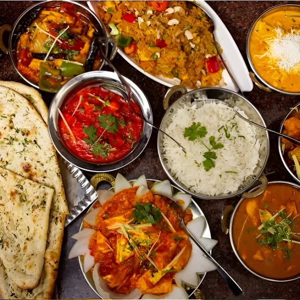 An overhead shot of various Indian dishes, including biryani, curries, rice, and naan bread.