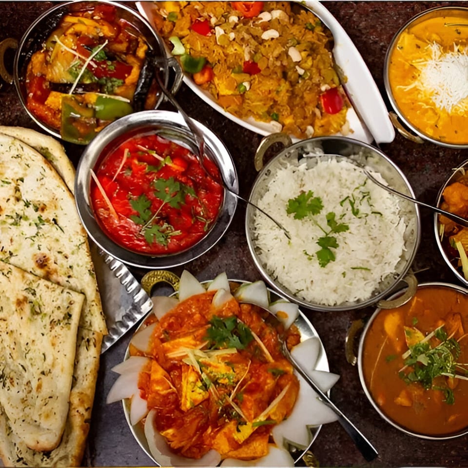 An overhead shot of various Indian dishes, including biryani, curries, rice, and naan bread.