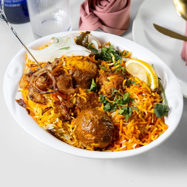 Pariwaar Delights' Chicken Biryani, garnished with fried onions, cilantro, and a lemon wedge.