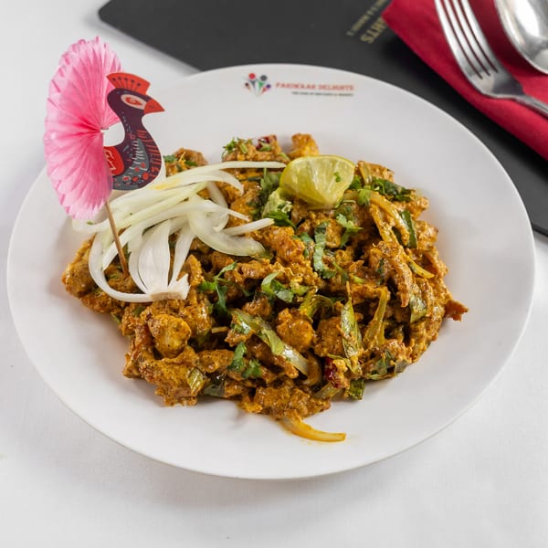 Pariwaar Delights' Indian chicken dish with onions, cilantro, and lime, garnished with a peacock decoration.