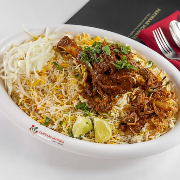 Pariwaar Delights' chicken biryani with a drumstick, fried onions, cilantro, and lime wedges.