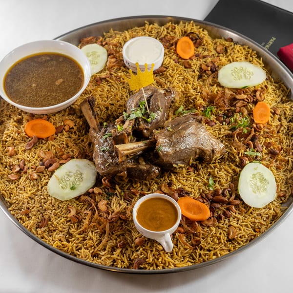 Pariwaar Delights' lamb biryani with a golden crown, served with soup and raita.