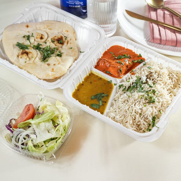 Indian takeout meal with naan, butter chicken, dal, rice, and a side salad.