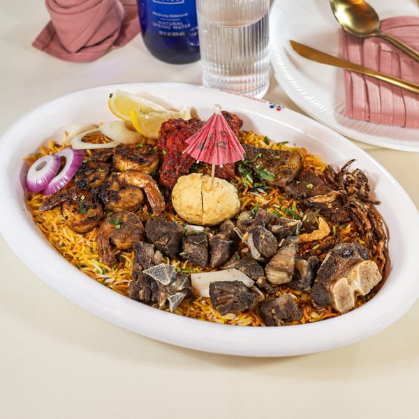 Pariwaar Delights' large biryani platter with shrimp, chicken, lamb, egg, and onions.