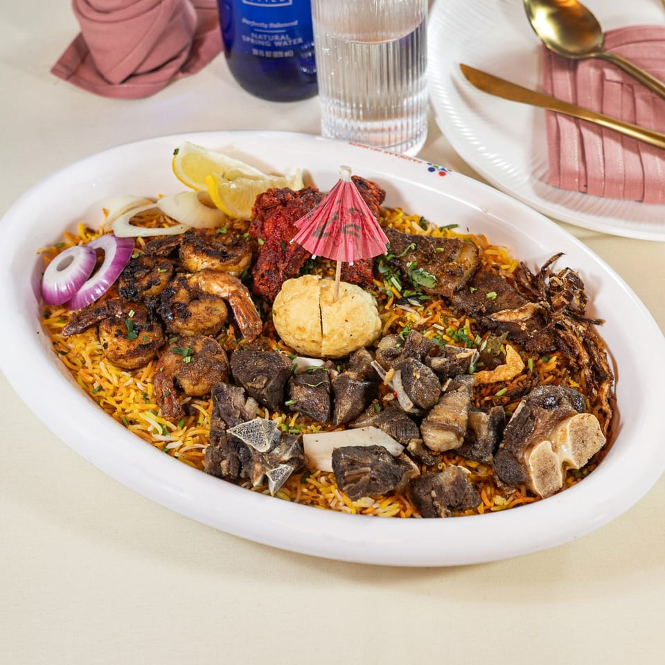 Pariwaar Delights' large biryani platter with shrimp, chicken, lamb, egg, and onions.